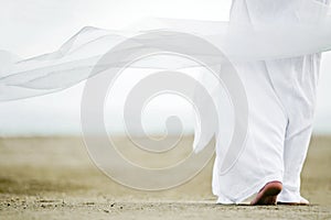Man in white walking on sand photo
