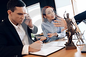 Man who divorces his wife consults on phone with lawyer. Disconcerted woman sits next to man talking on phone.