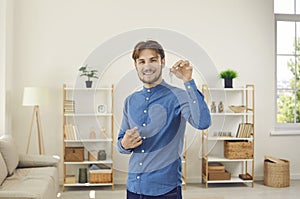 Man who is first buyer, homeowner or tenant of apartment shows keys while looking at camera.