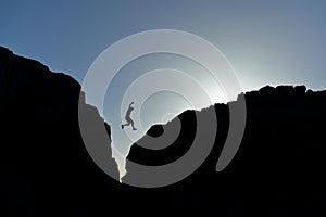 Man who jumped on the rocks in silhouette photo