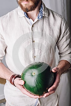 Man with whole green watermelon in hands