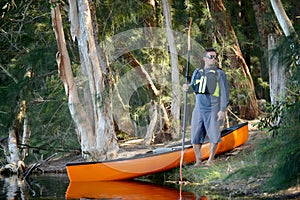 Man in the wilderness of a forest with a kayak