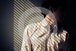 Man by window with shadows from blinds