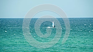 Man Windsurfing in the water during a sunny summer day. Shot. Beautiful view of the sea and windsurfer on a Sunny day