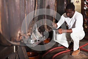 Man winemaker pouring wine to mug