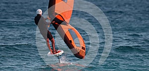 A man is wing foiling using handheld inflatable wings and hydrofoil surfboards