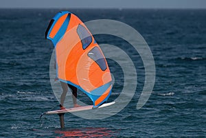 A man is wing foiling using handheld inflatable wings and hydrofoil surfboards