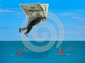 Man with wings made of money flying over school of sharks