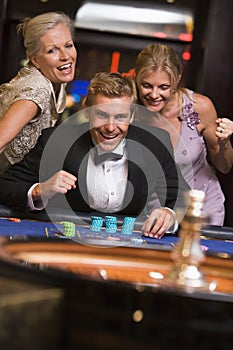 Man winning at roulette table surrounded by glamor