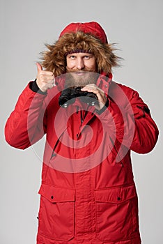 Man in winter jacket holding binoculars and gesturing thumb up