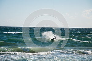 A man in winter surfin a wave iin a rough sea with a kite surf next to the shore in marbella, malaga photo