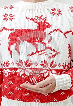 Man in winter sweater holding Christmas balls in hands. Close up