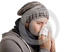 A man in winter time with disease has to sneeze and blow into a handkerchief isolated on white background