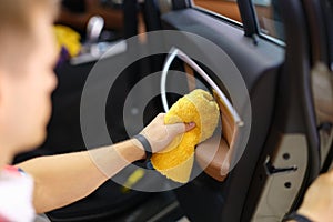 A man wipes a car door with a towel