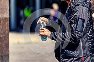 A man wipes with a handkerchief a water bottle bought in a store on a city street on a sunny day