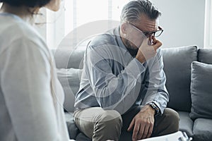 Man wipes his tears while talking to the therapist