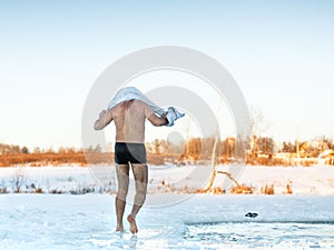 Man wipes towel after swimming in freezing hole