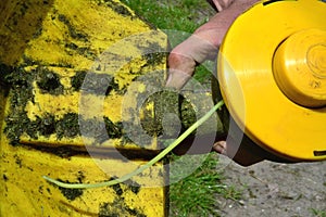 a man wipes a yellow lawnmower of cut grass