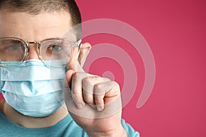 Man wiping foggy glasses caused by wearing disposable mask on  background, space for text. Protective measure during