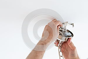 Man wiring ceiling light on white background