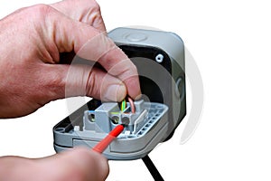 Man wiring an outdoor electric socket using an electrical screwdriver. Isolated on white background