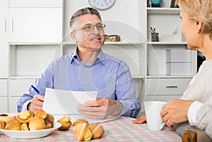 Man and woman 50-54 years old are discussing and studying important contract