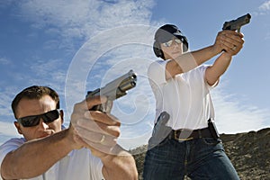 Man And Woman Aiming Hand Guns At Firing Range photo