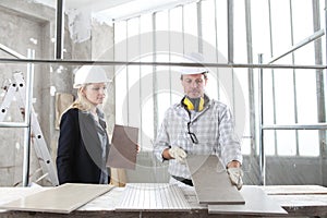 Man and woman architect interior designer and foreman worker together with tiles samples and decorative materials discussing the