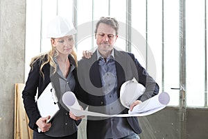 Man and woman architects or engineers work together discussing with blueprint in the inside the construction building site