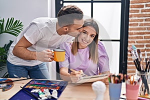 Man and woman artists couple drawing on notebook drinking coffee at art studio