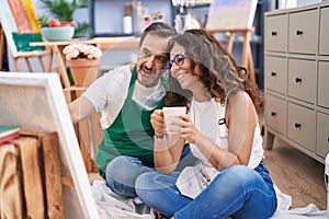Man and woman artists drinking coffee drawing at art studio