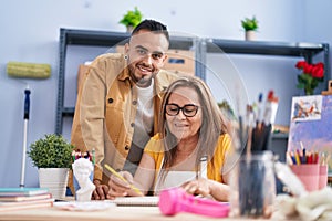 Man and woman artists smiling confident drawing on notebook at art studio