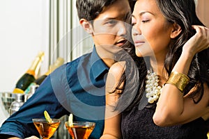 Man and woman in asia at bar with cocktails