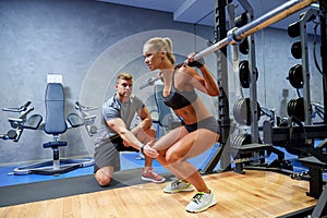 Man and woman with bar flexing muscles in gym