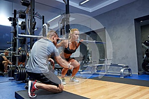 Man and woman with bar flexing muscles in gym