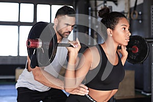 Man and woman with barbell flexing muscles in gym