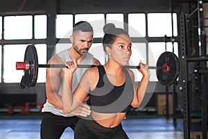 Man and woman with barbell flexing muscles in gym