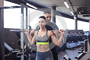 Man and woman with barbell flexing muscles in gym