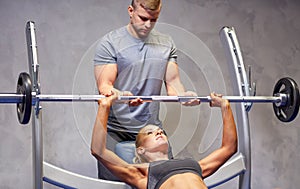 Man and woman with barbell flexing muscles in gym