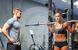 Man and woman with barbell flexing muscles in gym