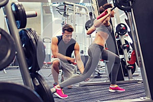 Man and woman with barbell flexing muscles in gym