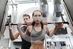 Man and woman with barbell flexing muscles in gym