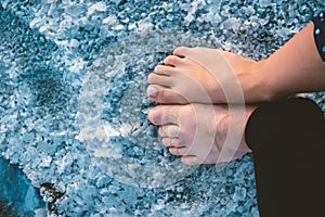 A man and a woman with bare feet walk on the surface of a salt lake