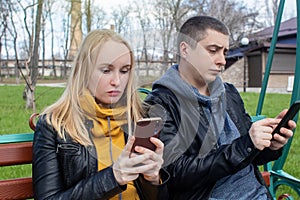 Man and a woman are both sitting on a date and sipping into their smartphones. Concept of social media addiction, getting out of