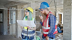 Man and woman builders reading house project speaking by walkie-talkie at construction site