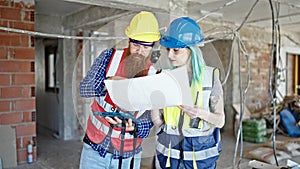 Man and woman builders using touchpad reading house project at construction site