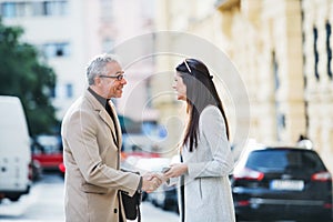 Man and woman business partners standing outdoors in city of Prague, shaking hands.