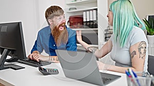 Man and woman business workers using laptop and computer high five for achievement at office
