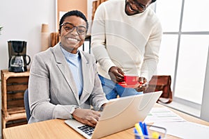 Man and woman business workers using laptop drinking coffee at office