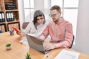 Man and woman business workers using laptop and touchpad working at office